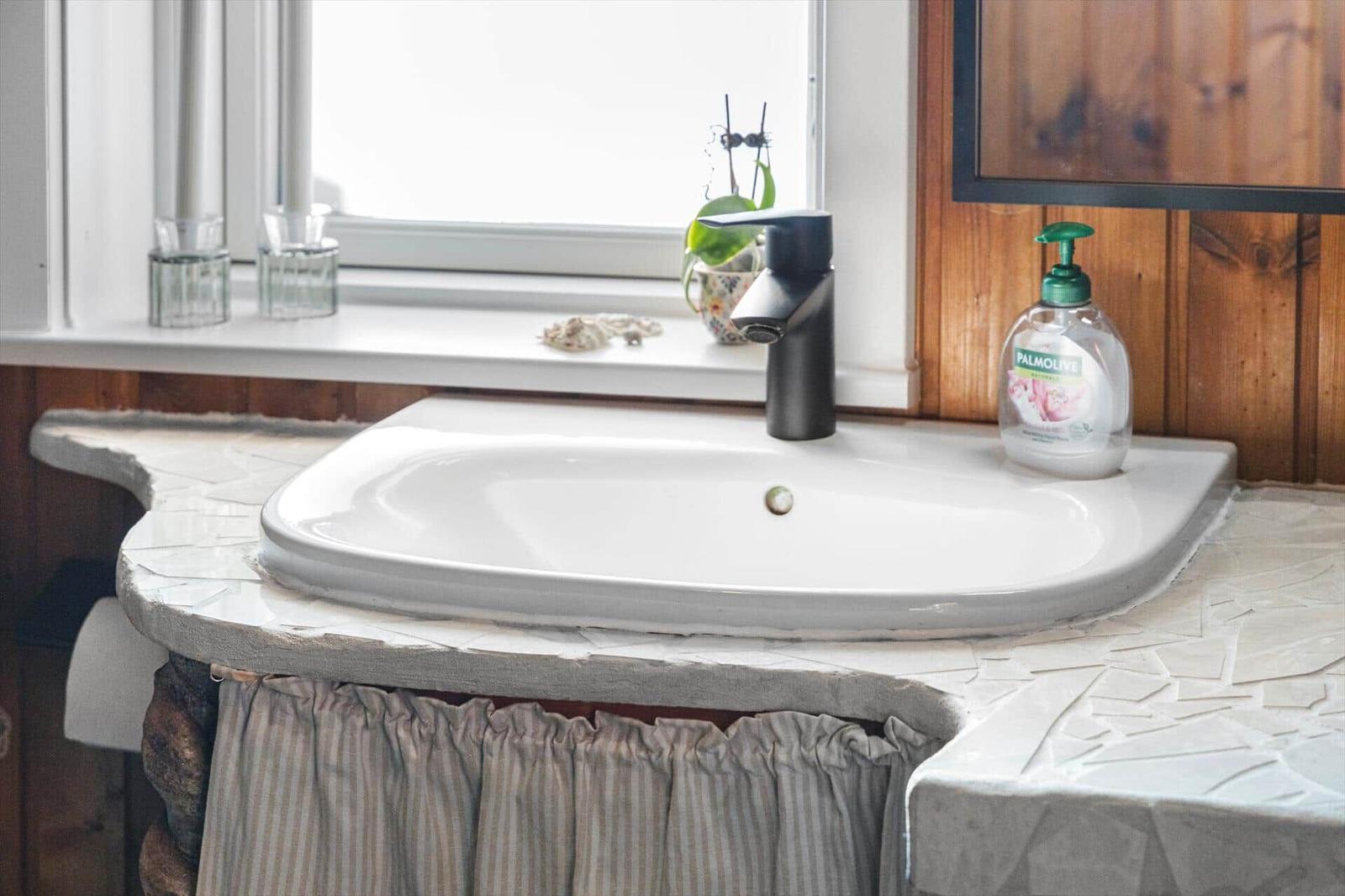 Waschbecken mit Mosaikarbeitsplatte, Fenster und Spülmittelflasche