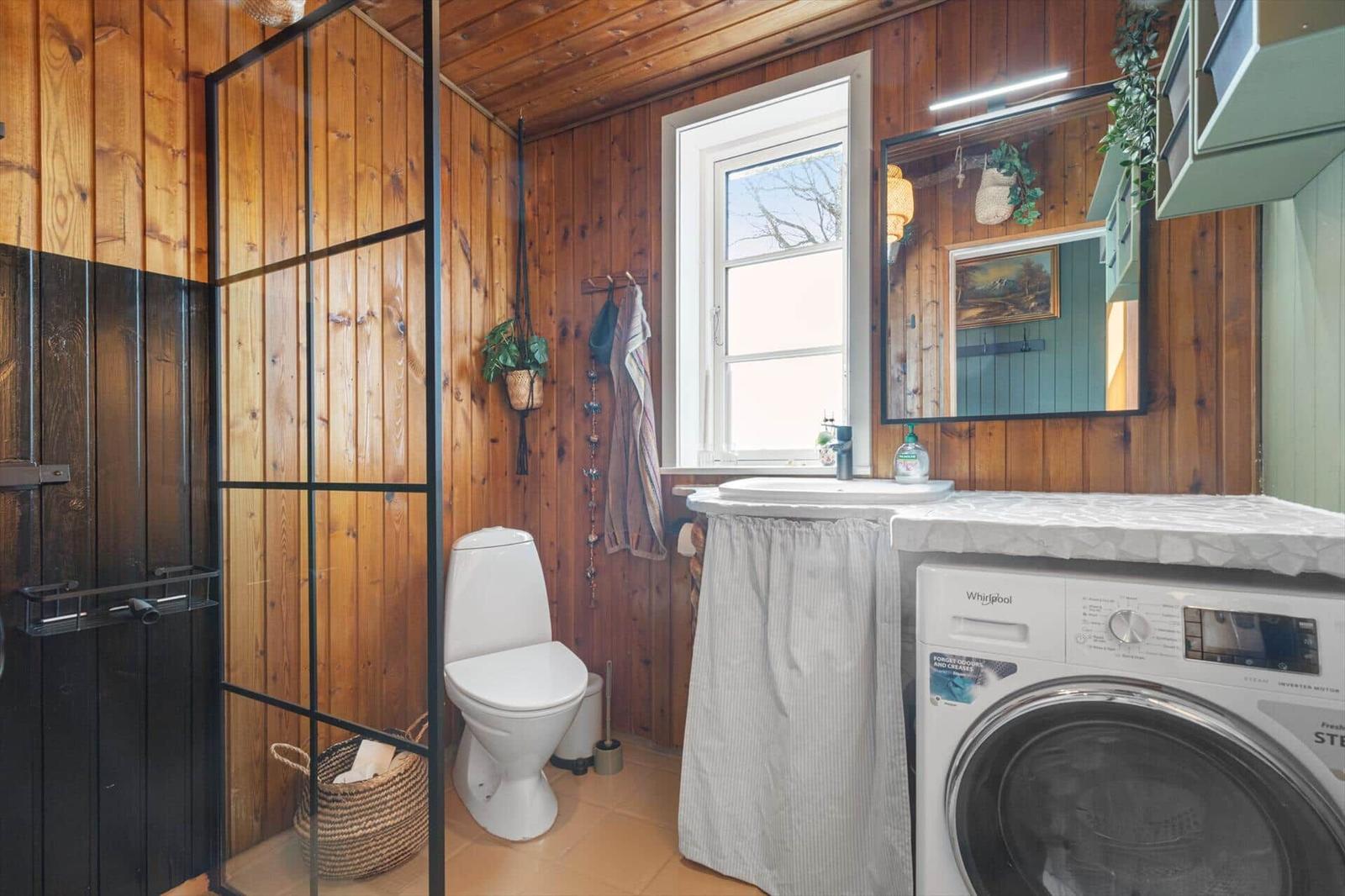 Badezimmer mit Dusche, Toilette, Waschbecken und Waschmaschine.