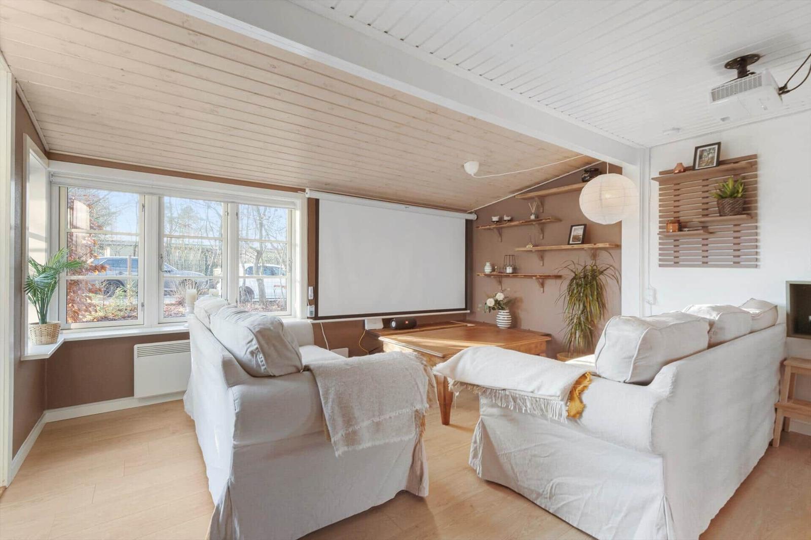 Wohnzimmer mit zwei Sofas, Fernseher und großen Fenstern.