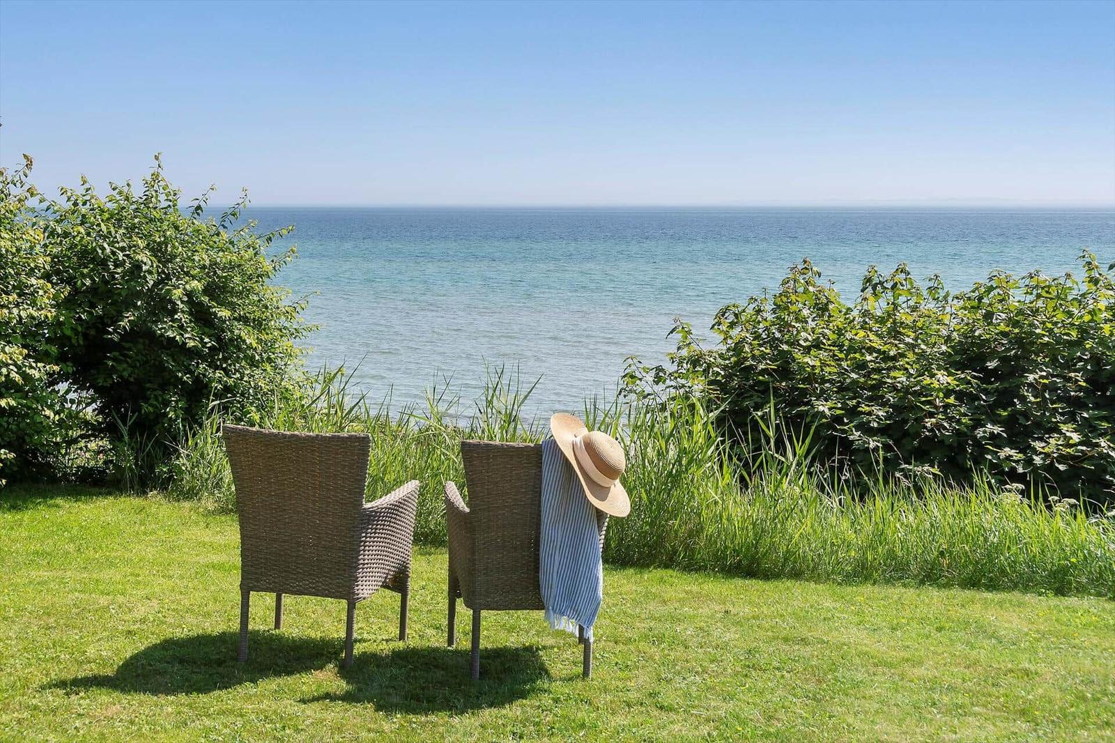 Zwei Stühle auf einer Wiese mit Blick auf das Meer.