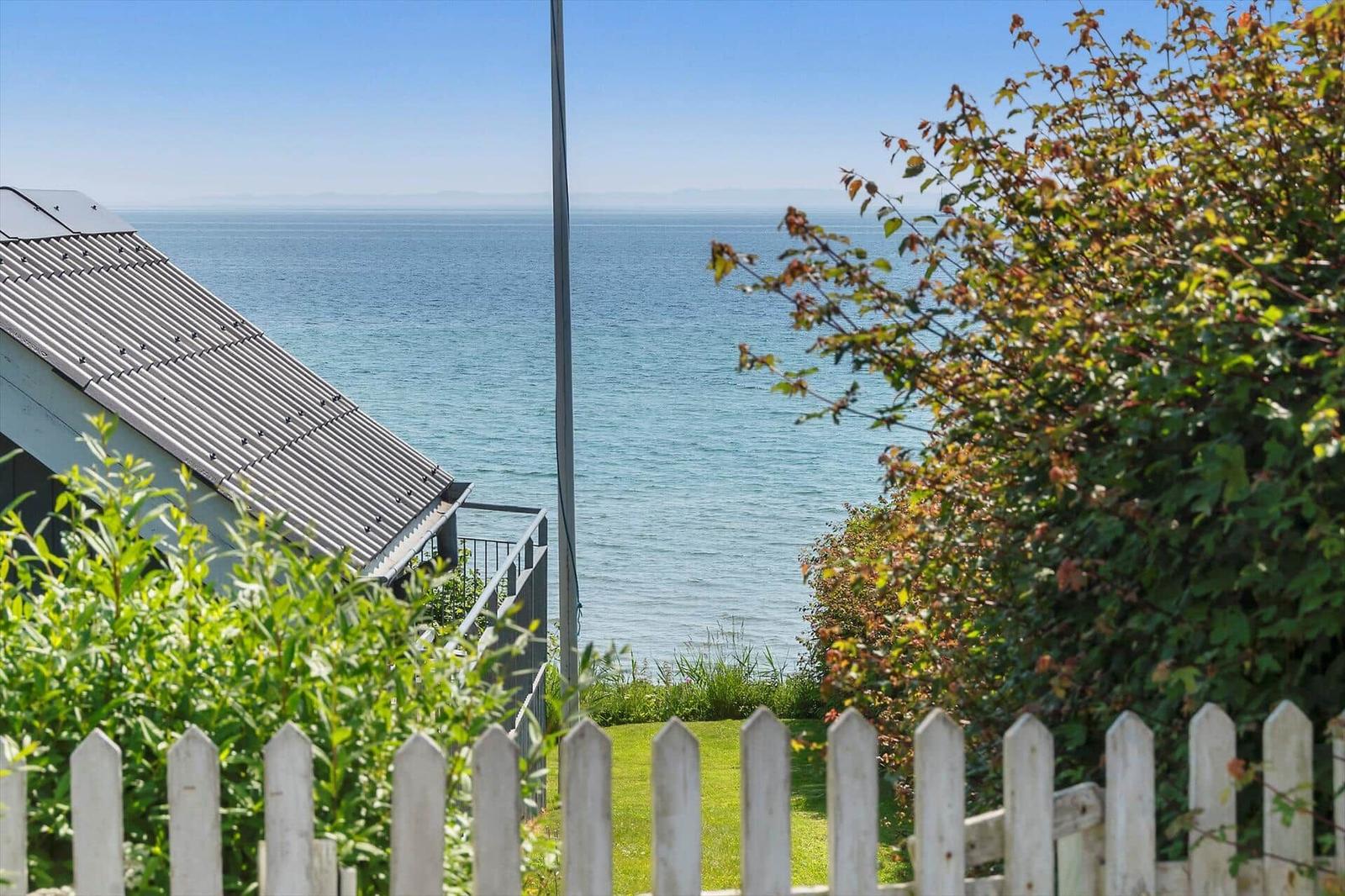 Vom Garten aus Blick auf das Meer mit weißem Zaun und grüner Vegetation.