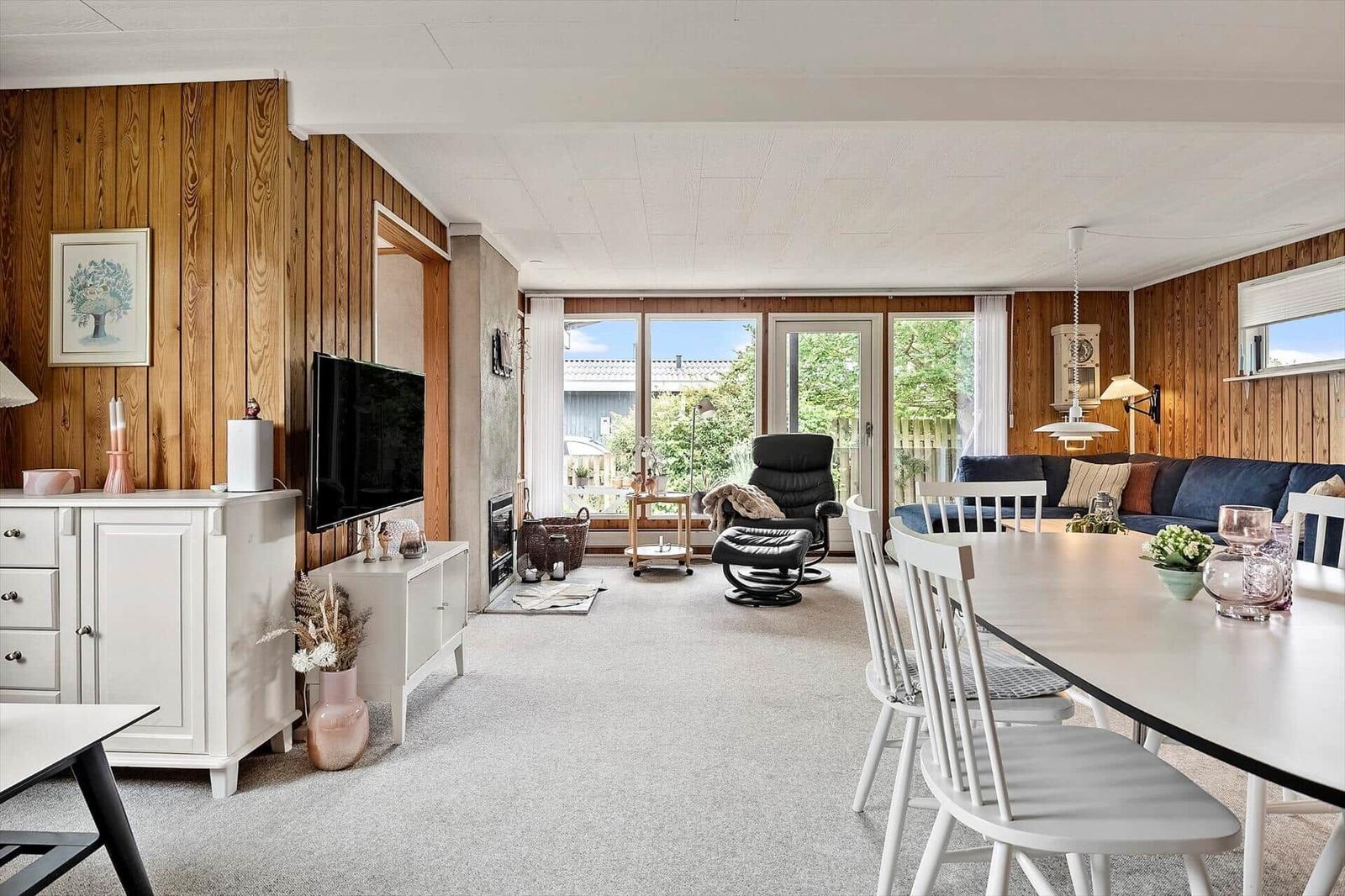 Wohn- und Essbereich mit Holzwand, TV, Sofa und Esstisch.