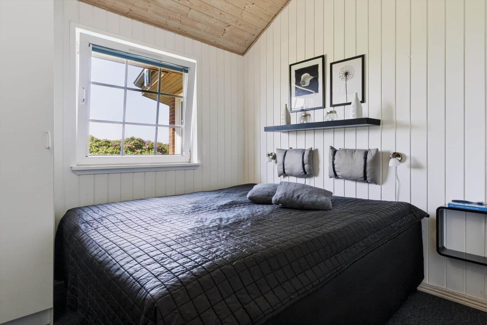 Schlafzimmer mit Bett, Fenster und Wandregal.
