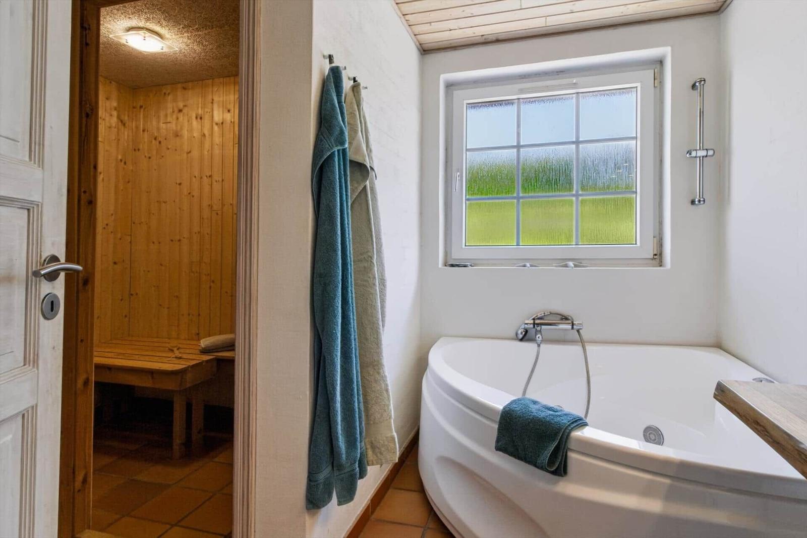 Bad mit Whirlpool und Sauna im Hintergrund.