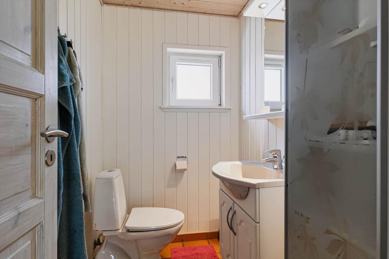 Badezimmer mit Toilette, Waschbecken und Dusche mit Glaswand.