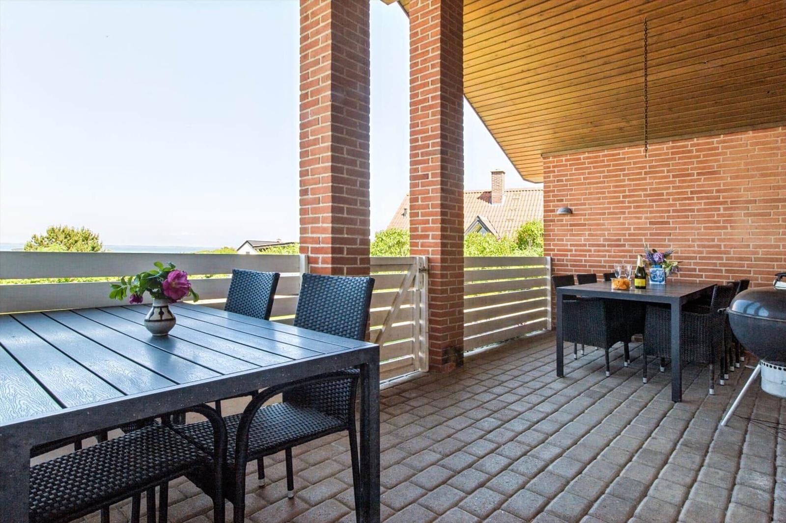 Terrasse mit Tisch, Stühlen, Grill und Blick auf die Landschaft.