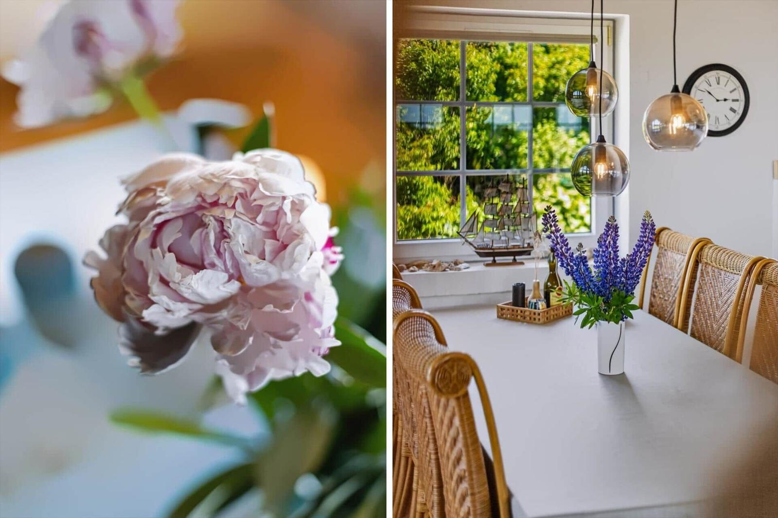 Ein Esszimmer mit Blick auf grüne Bäume und eine Blumenvase auf dem Tisch.