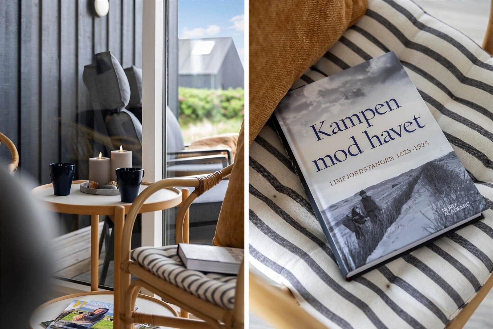 Ein Raum mit Sitzgelegenheiten und Blick auf die Außenterrasse. Ein Buch liegt auf einem gestreiften Kissen.