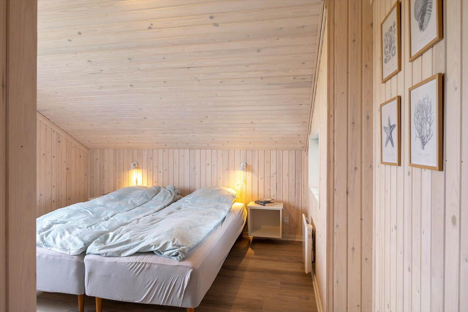 Schlafzimmer mit Doppelbett, Holzwandverkleidung und Wandbildern