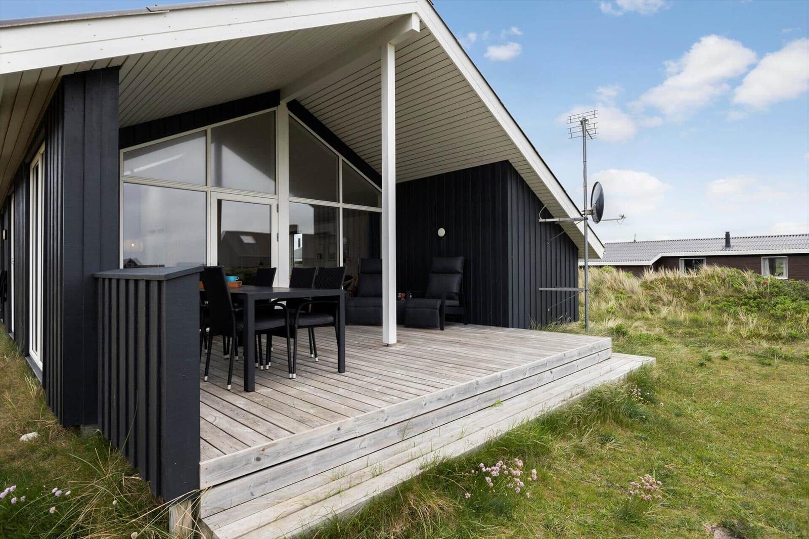Haus mit Terrasse, Tisch und Stühlen, Sitzgelegenheiten und Satellitenschüssel.