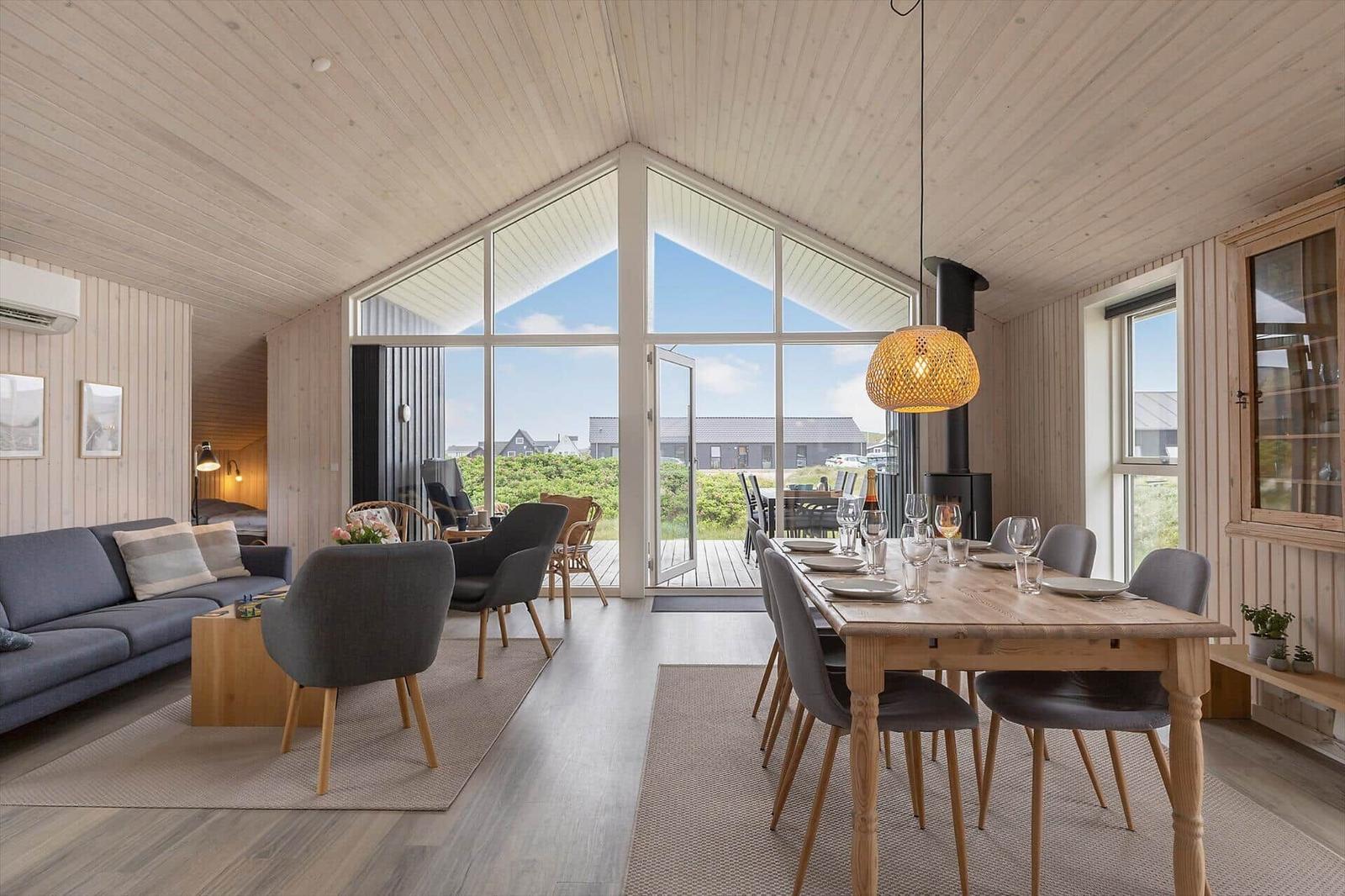 Wohn- und Essbereich mit Holzdecke, großem Fenster und Esstisch mit Stühlen.