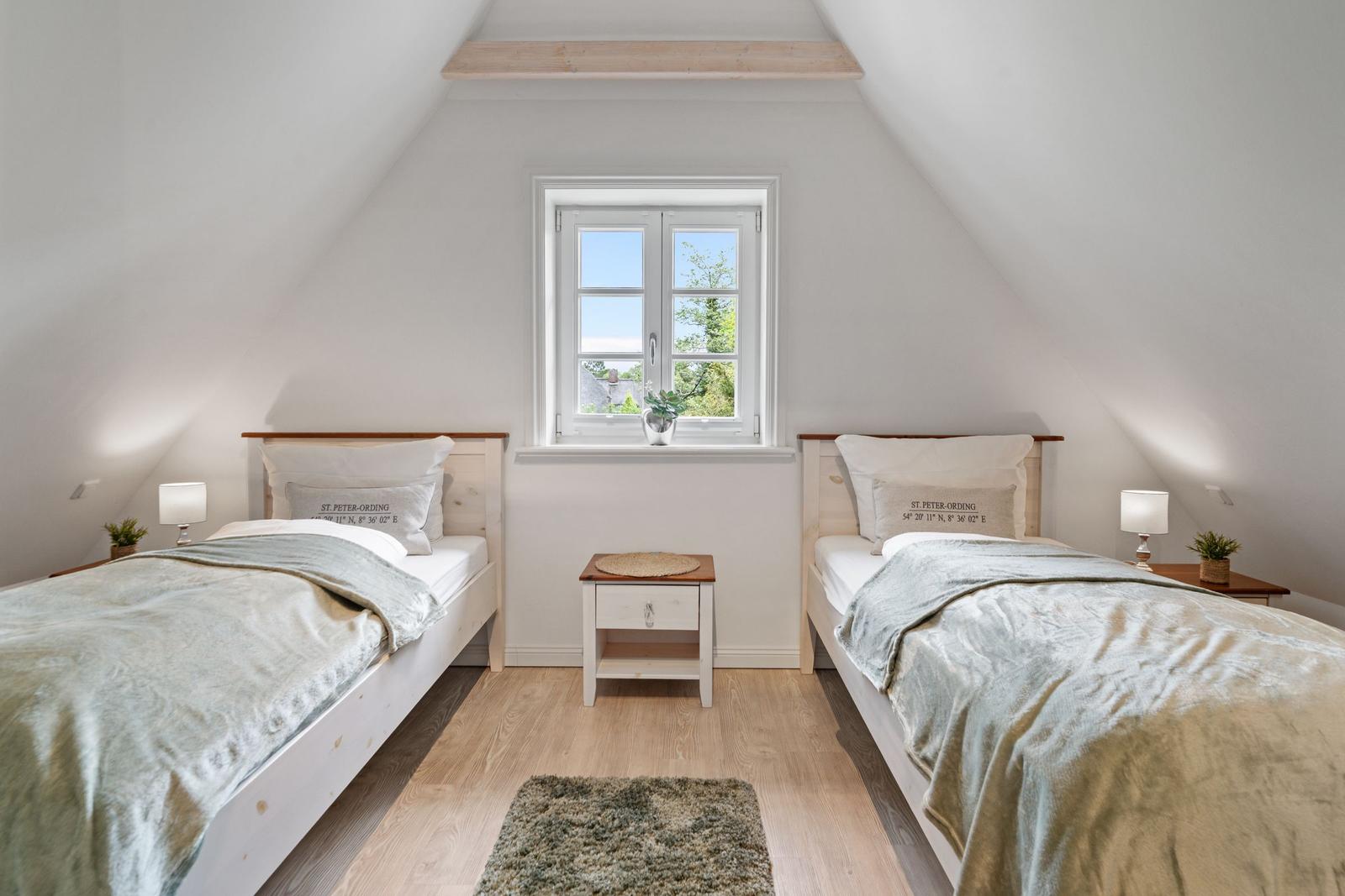 Zwei Betten in einem Dachzimmer mit Fenster und Holzboden.