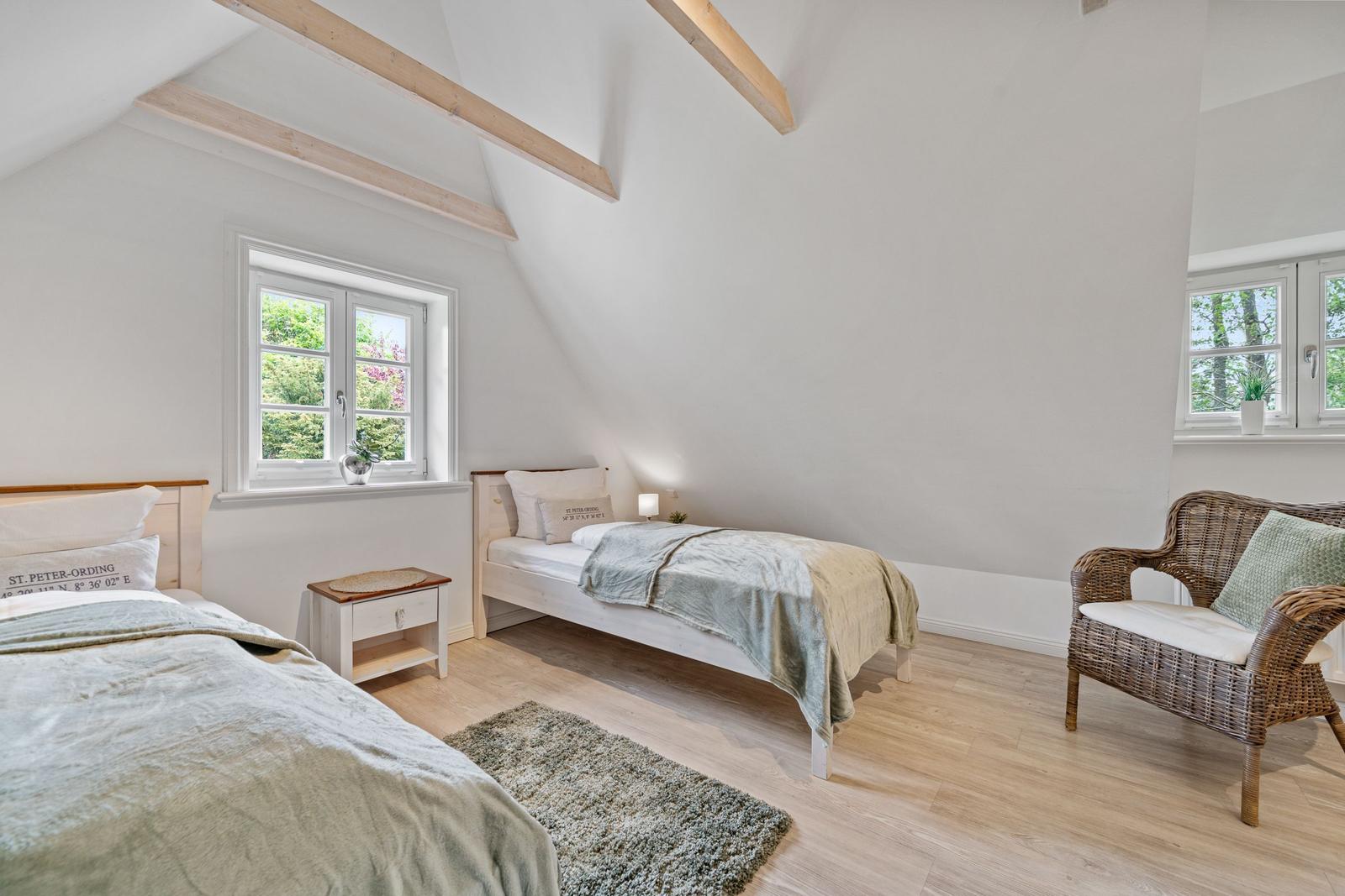 Zwei Betten, ein Sessel und Fenster mit Blick auf Grün.