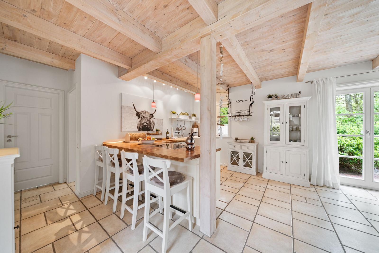 Küche mit Holzdecke, Sitzgelegenheit und Blick auf den Garten.