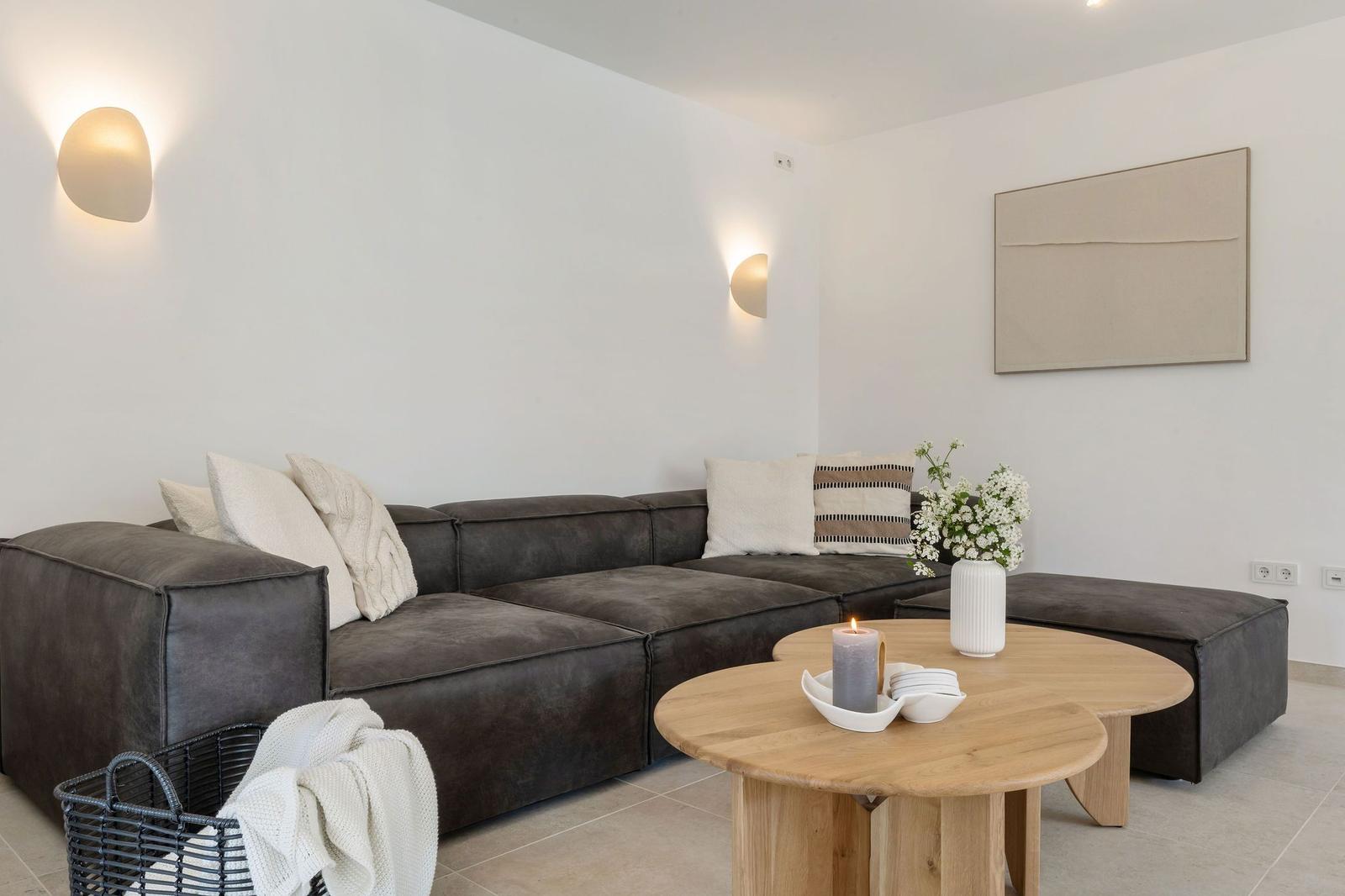 Ein Wohnzimmer mit einem dunkelbraunen Sofa, einem runden Holztisch und einer Wandlampe.