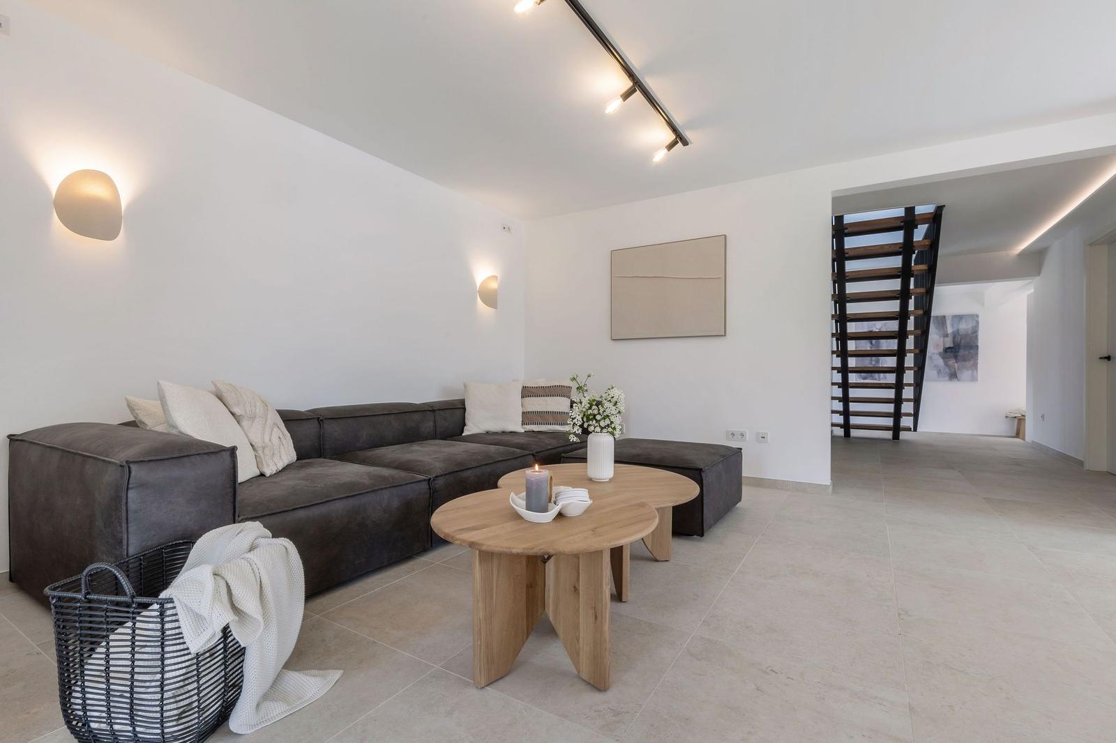Wohnbereich mit Sofa, Tisch und Treppenaufgang