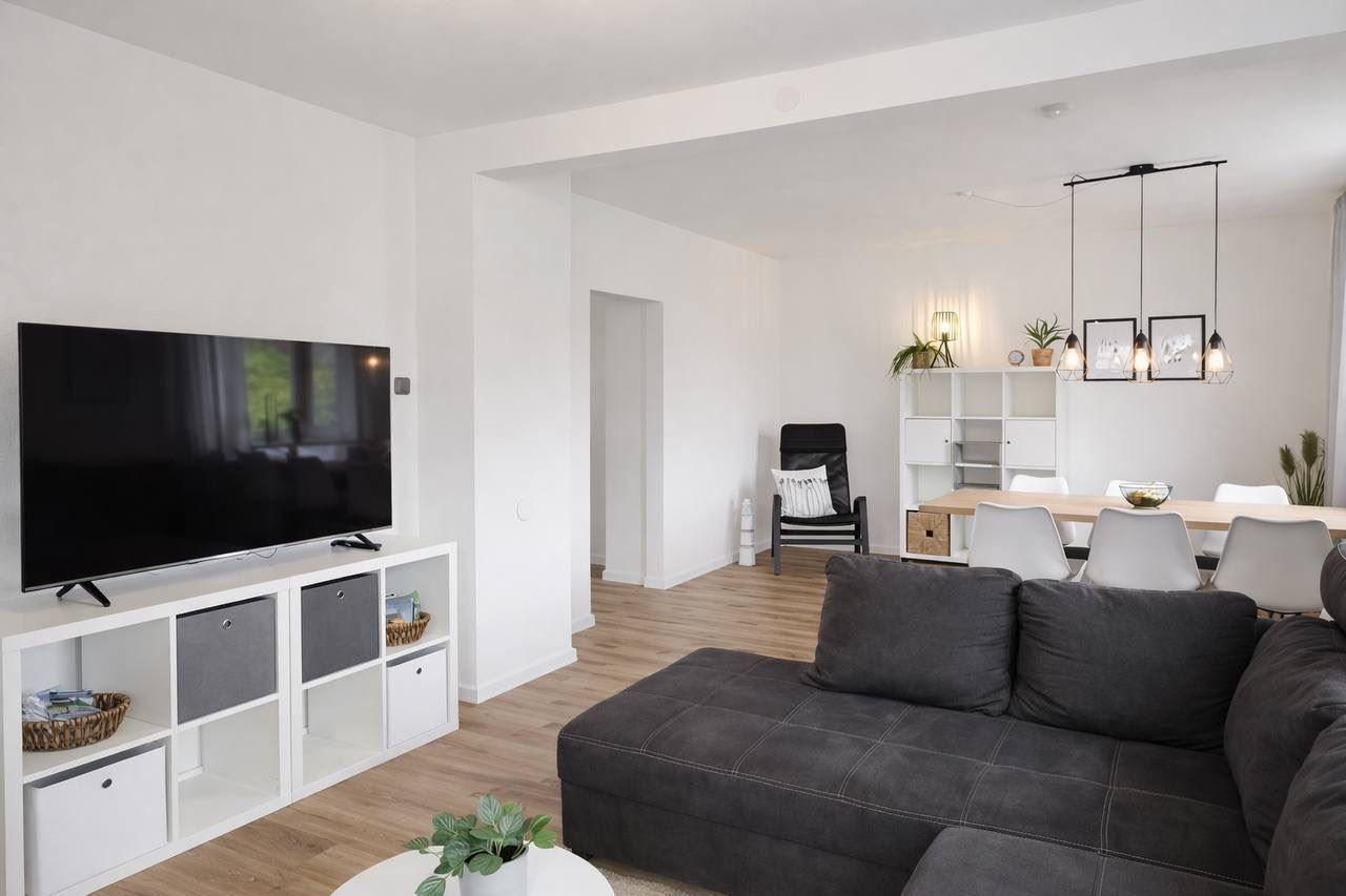 Wohn- und Essbereich mit Sofa, Fernseher und Esstisch.