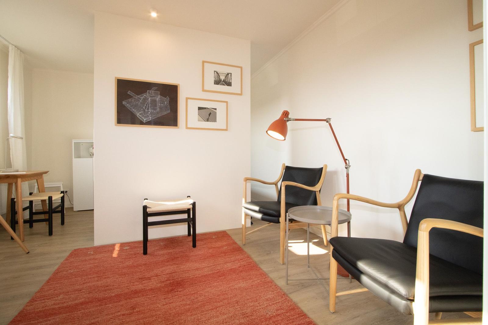 Wohnbereich mit zwei Sesseln, Teppich und Stehlampe an der Wand.