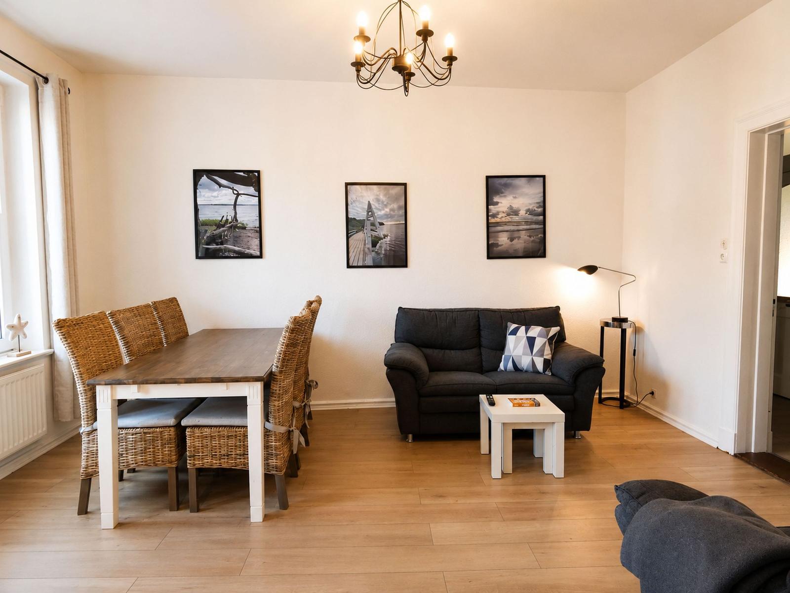 Wohn- und Essbereich mit Sofa, Esstisch und Wandbildern.
