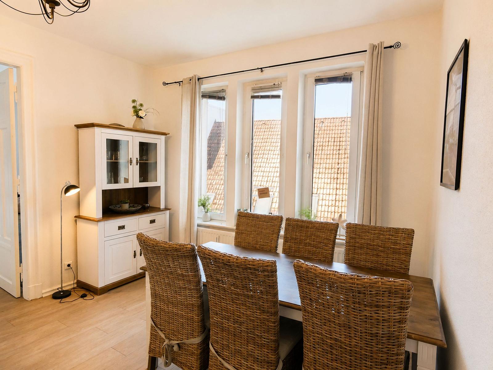 Esszimmer mit Esstisch, sechs Stühlen und Fenstern mit Blick auf Dächer.