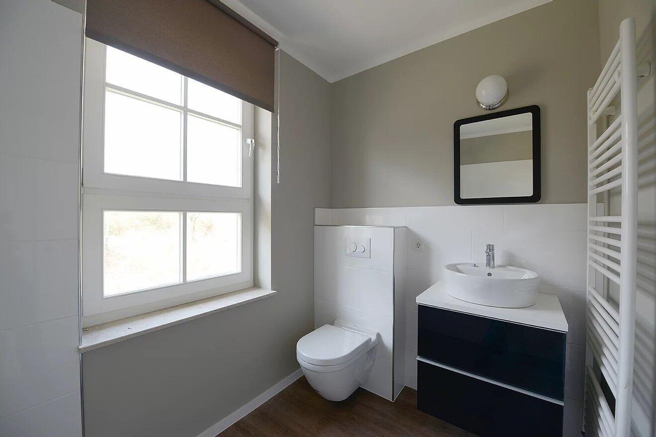 Badezimmer mit Toilette, Waschbecken und Fenster