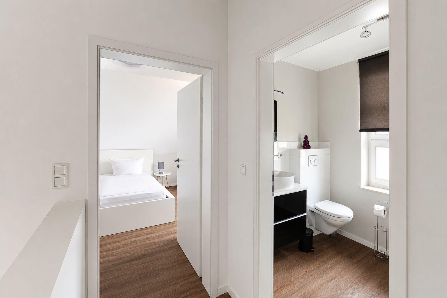 Schlafzimmer und Bad mit moderner Einrichtung und Holzboden
