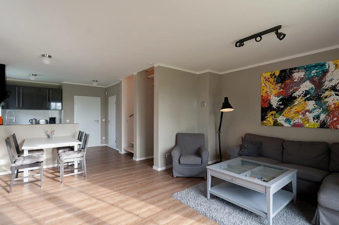 Wohnbereich mit Sofa, Sessel, Esstisch und Küchenbereich.