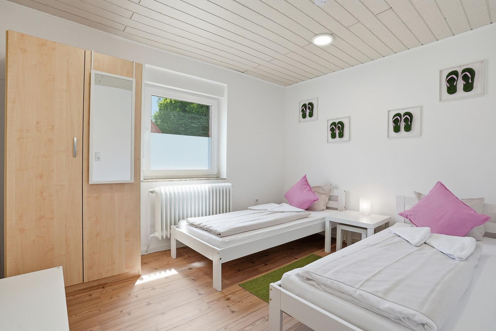 Zwei Einzelbetten, Schrank, Fenster und Wanddekoration mit Flipflops.