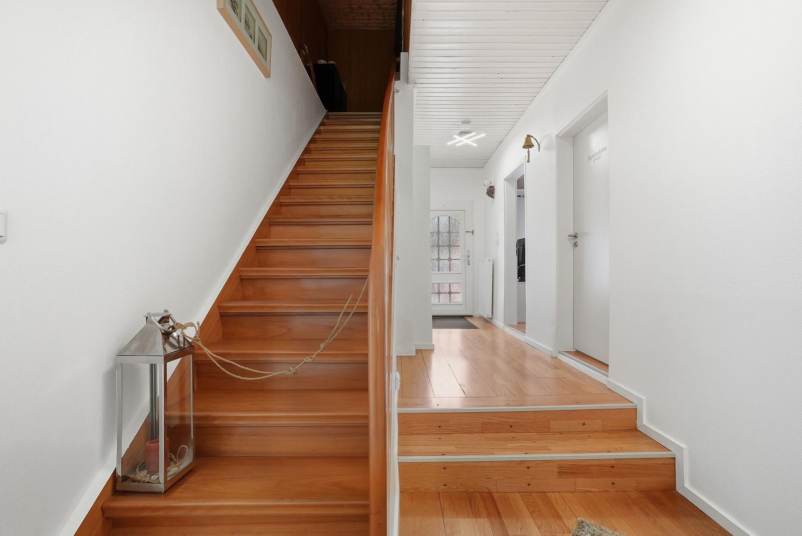 Haus mit Holztreppe und Flur. An der Treppe hängt eine Laterne.