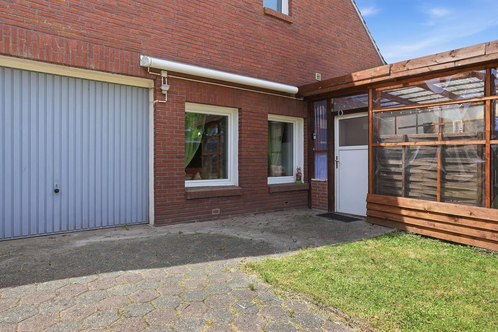 Rotes Backsteingebäude mit Garage, Terrasse und Gartenbereich.