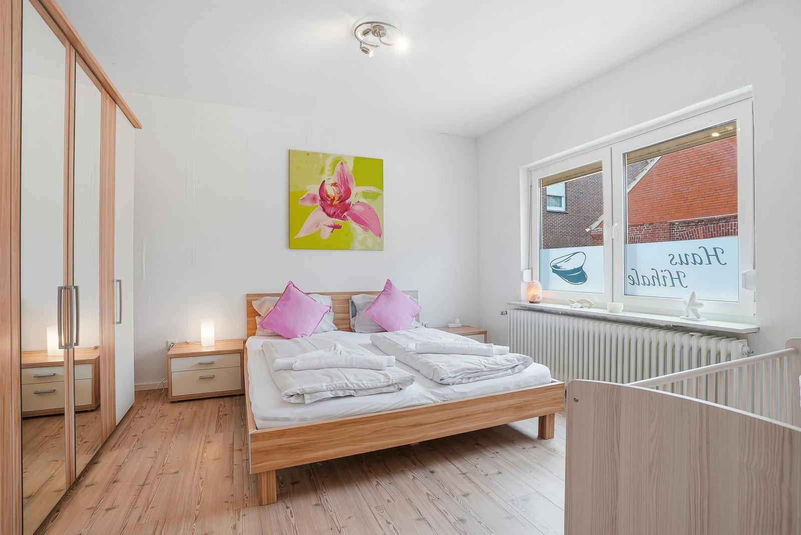 Schlafzimmer mit Holzbett, Kleiderschrank und Fenster mit Blick auf Gebäude.