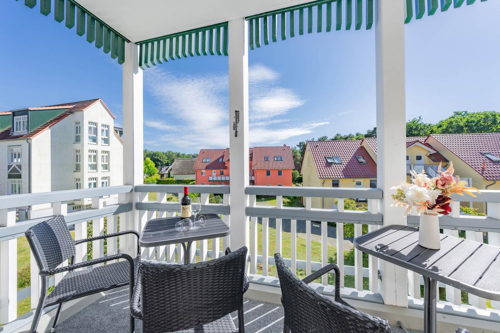 Terrasse mit Tisch, Stühlen und Blick auf Häuser und Grünflächen.