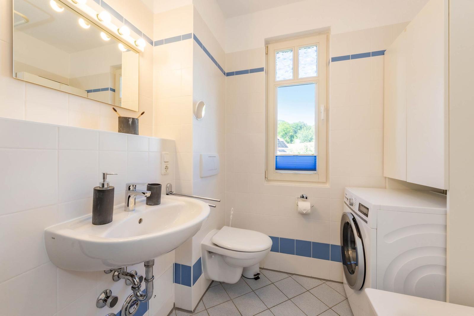 Badezimmer mit Waschmaschine, Toilette und Fenster