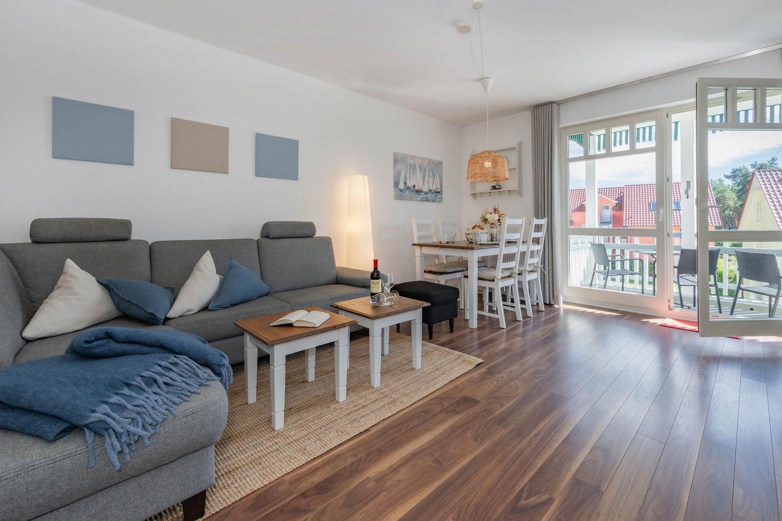Wohn- und Essbereich mit Sofa, Tisch und Blick auf Balkon.