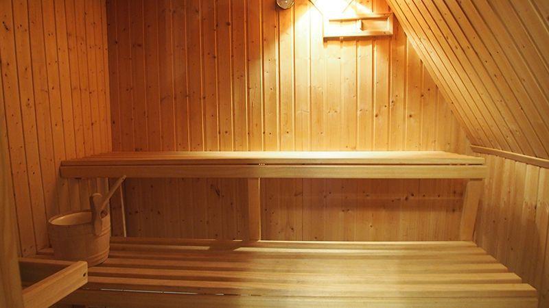 Sauna mit Holzwand, Sitzbank und Eimer