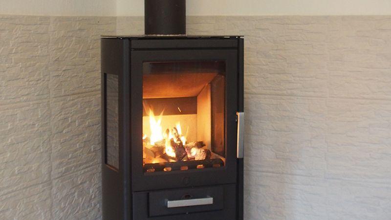 Holzofen mit brennenden Holzscheiten an der Wand