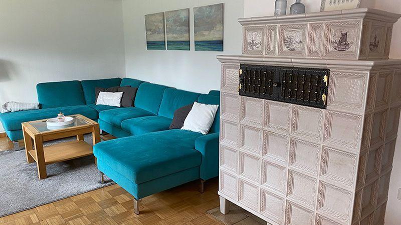 Wohnzimmer mit türkisfarbenem Sofa, Holztisch und dekorativem Kamin.