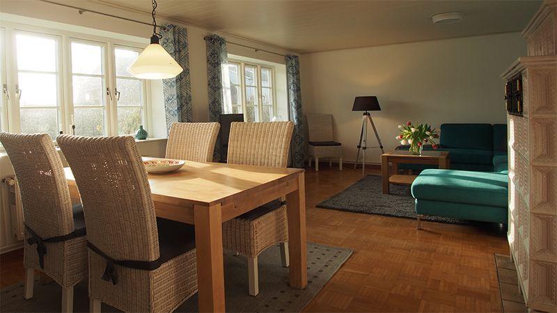 Essbereich mit Holztisch und Stühlen. Wohnbereich mit Sofa und Beistelltisch.