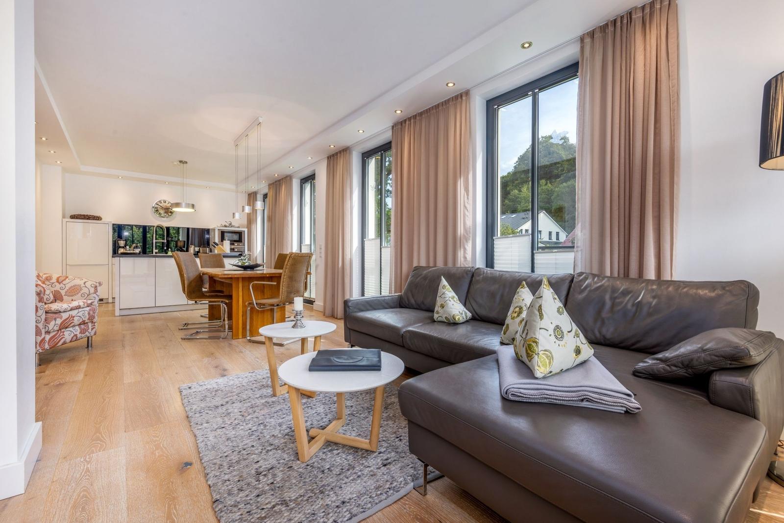 Wohn- und Essbereich mit Sofa, Tisch und Küchenzeile im Hintergrund.