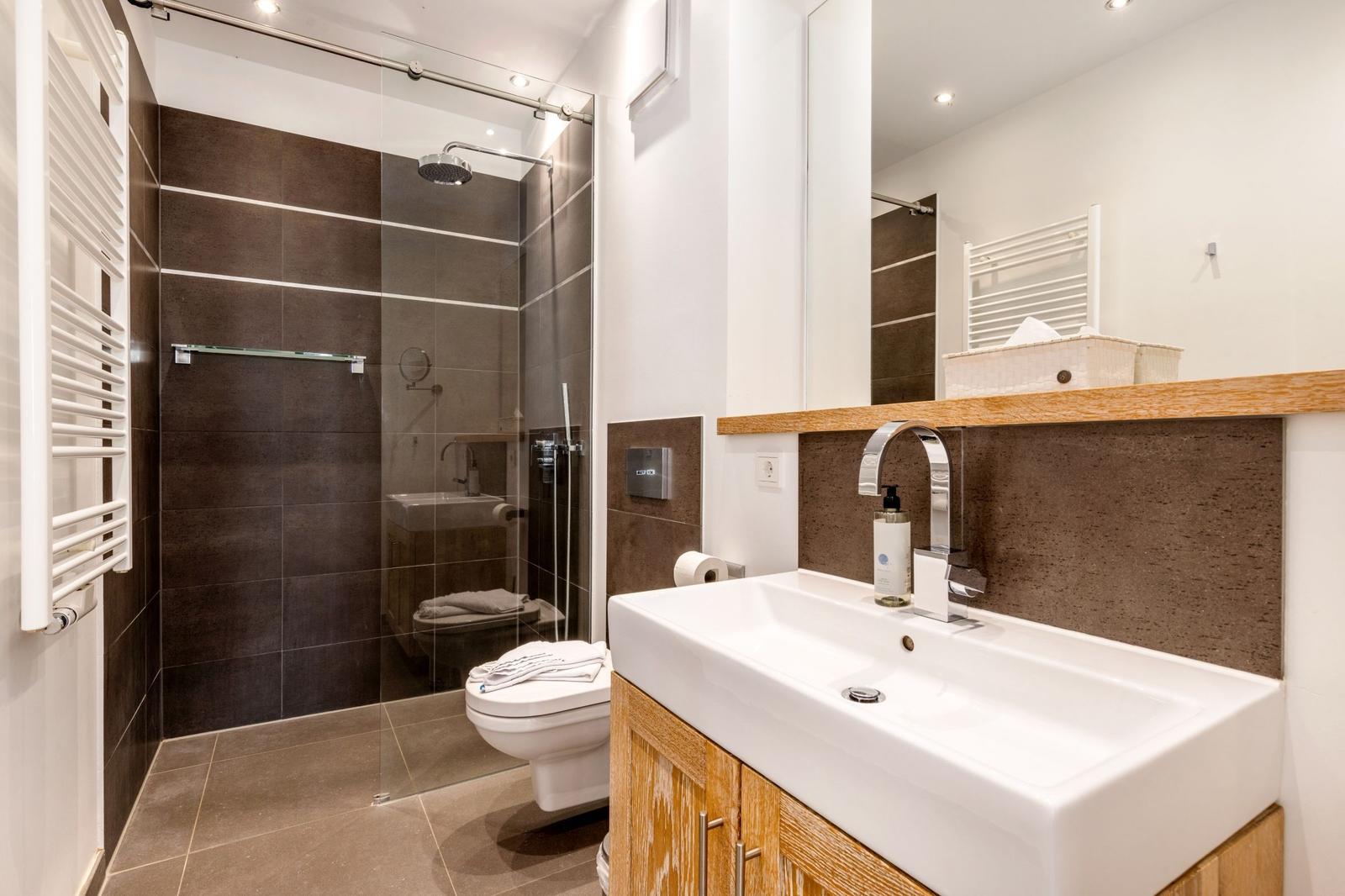 Badezimmer mit Dusche, Toilette und Waschbecken mit Spiegel.