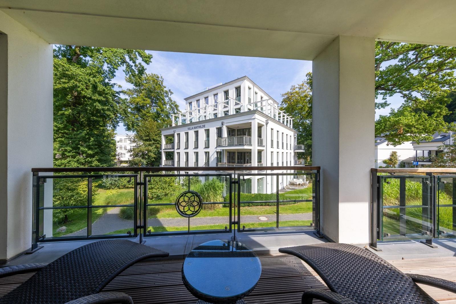 Terrasse mit Tisch und Stühlen, Blick auf Villa Mathilde und grüne Umgebung.