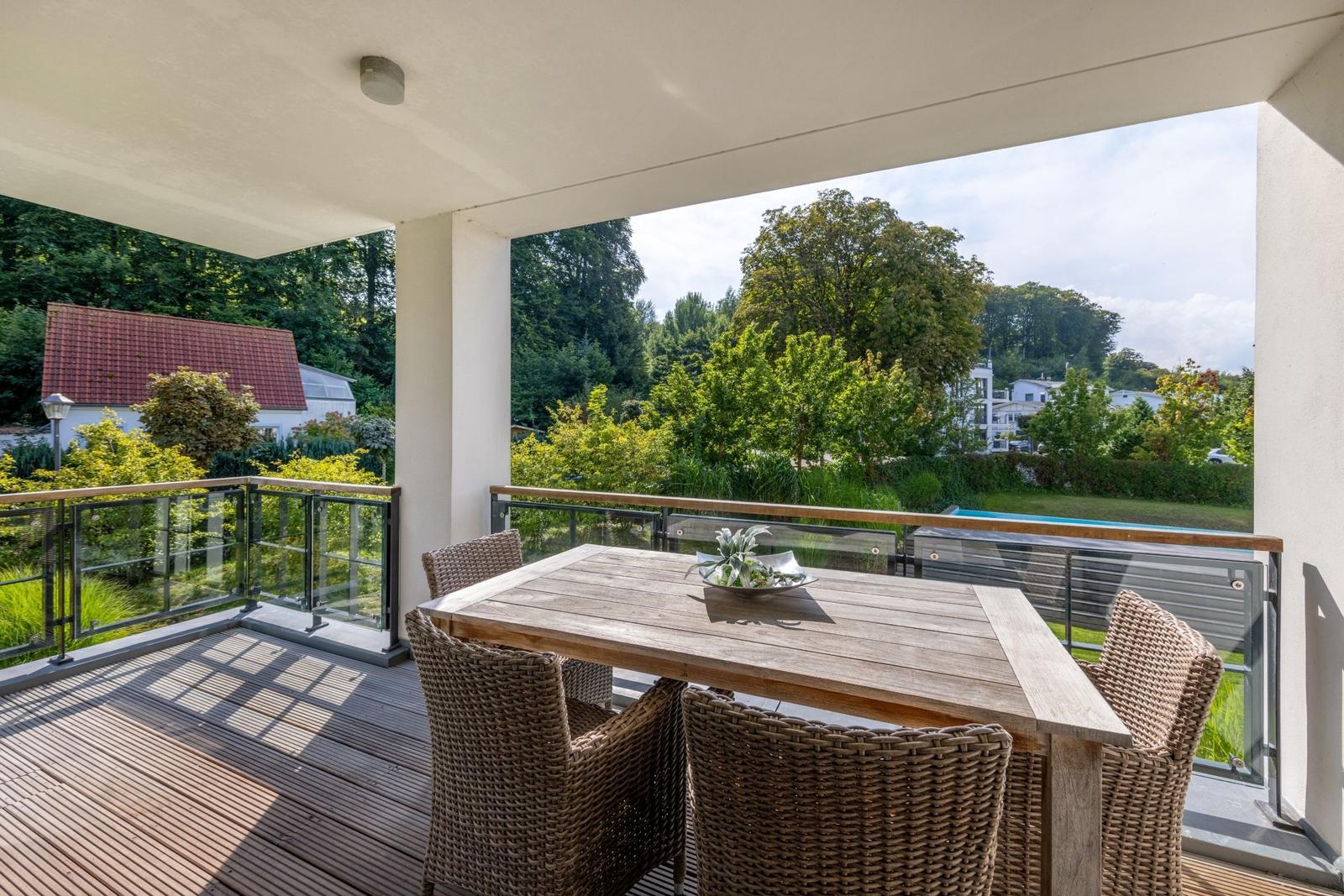 Terrasse mit Tisch und Stühlen. Blick auf grüne Landschaft und Pool.