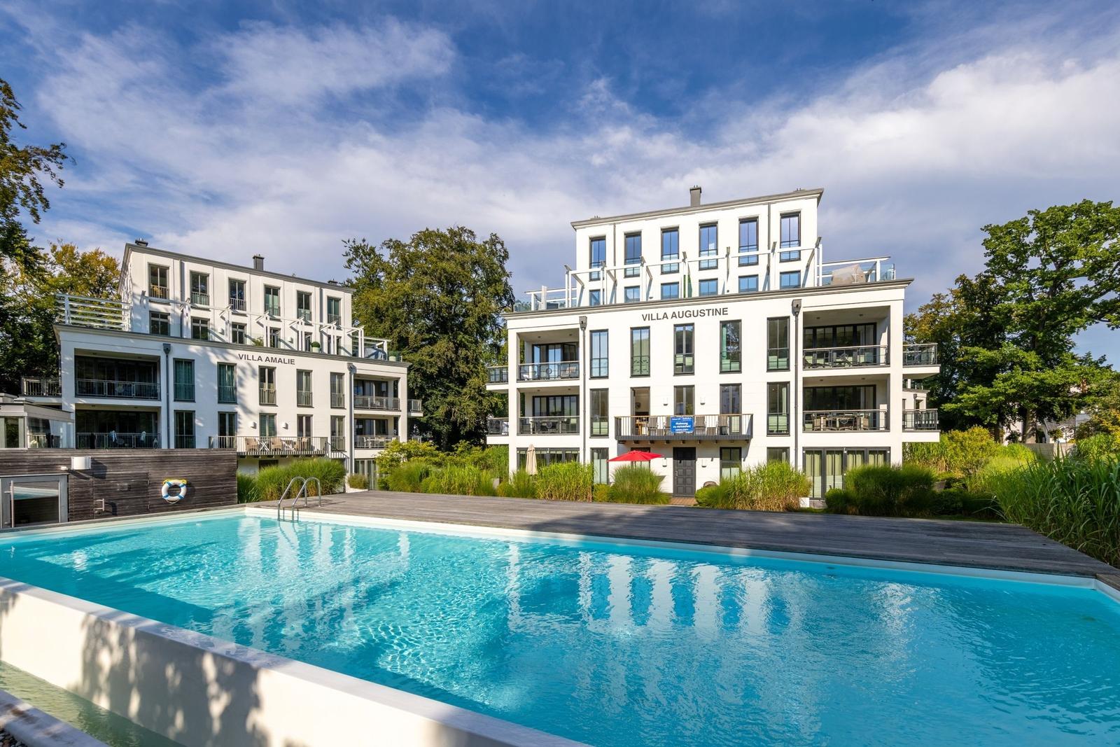Pool mit Blick auf Villa Augustine und Villa Amalie. Modernes Gebäude mit Balkonen.