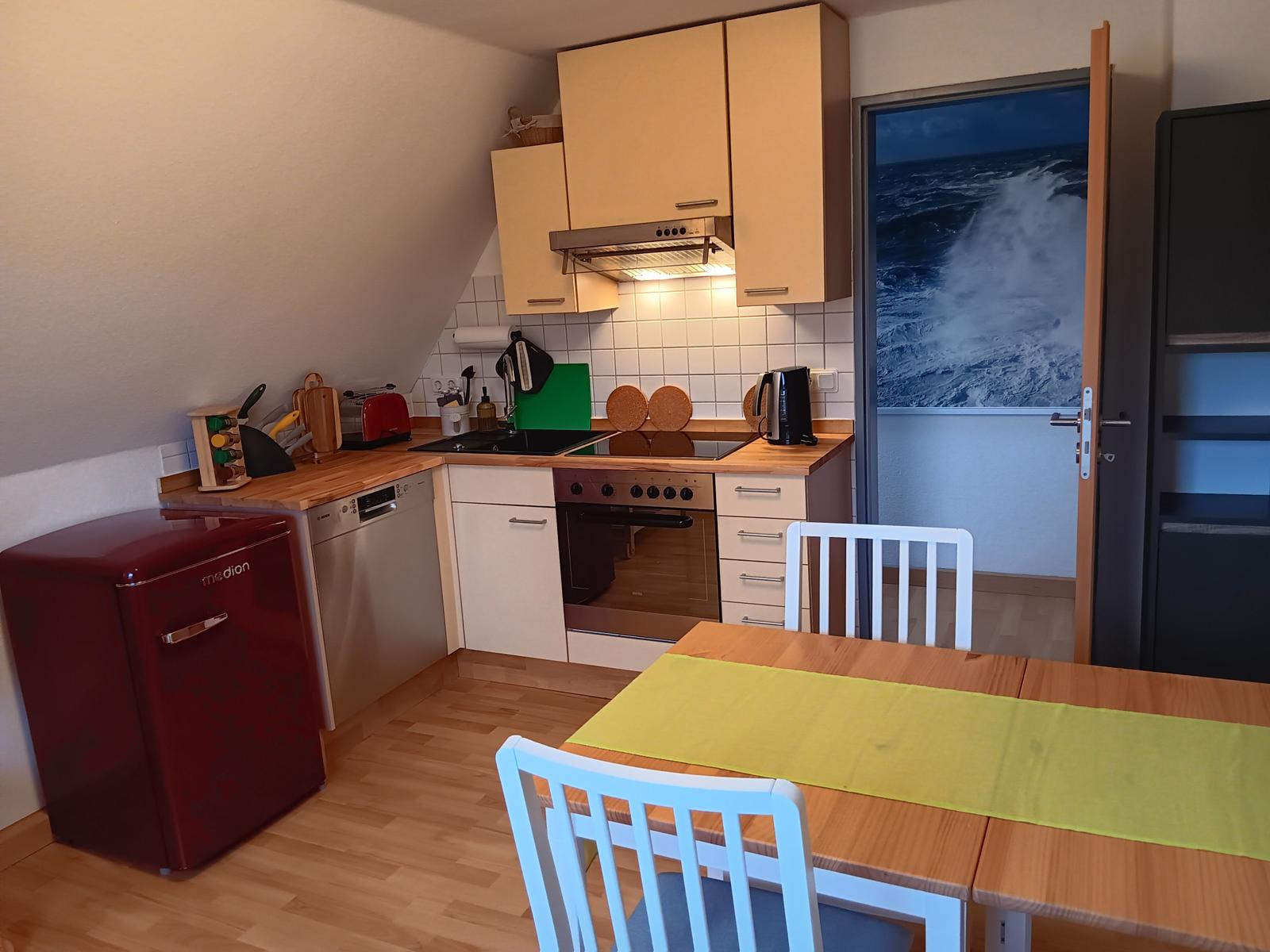 Küche mit Essbereich, rotem Kühlschrank und Blick auf das Meer.