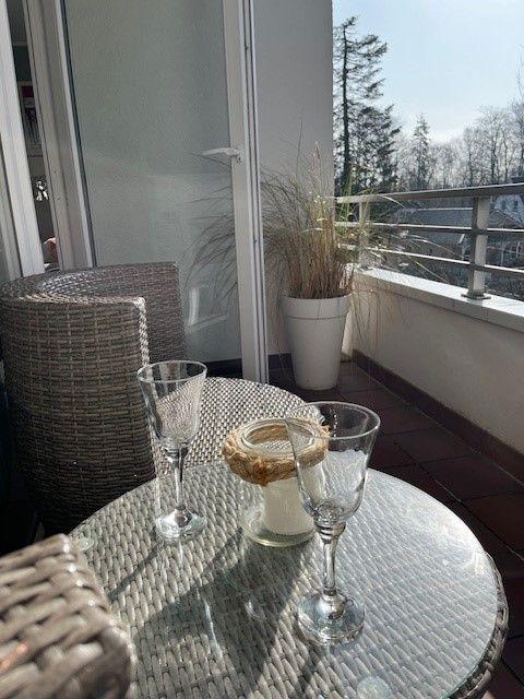Terrasse mit Tisch, Stühlen und Pflanze. Blick auf Bäume und Himmel.