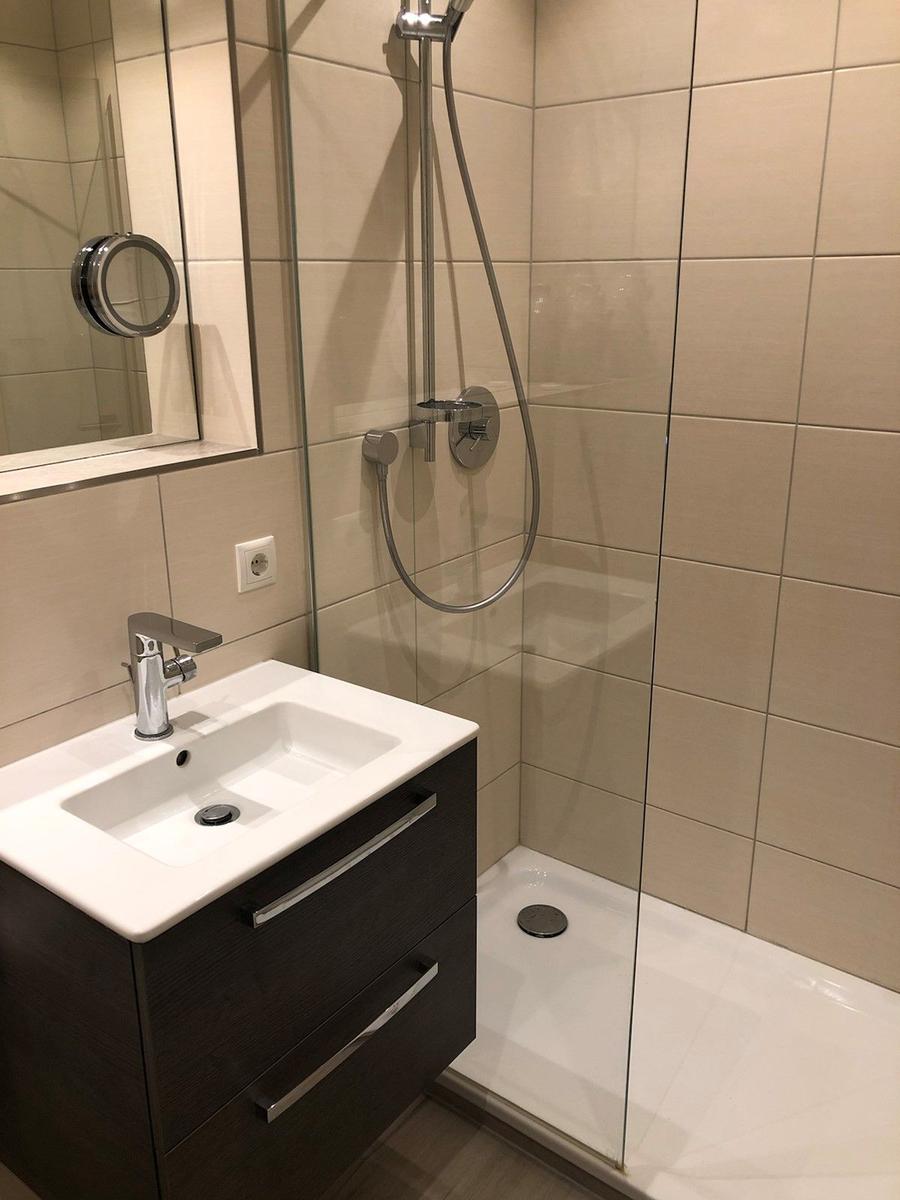 Badezimmer mit Dusche, Waschbecken und Spiegel