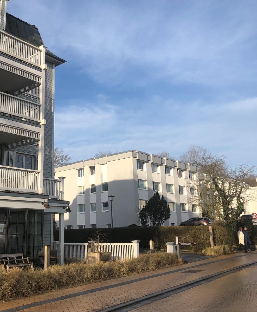 Moderne Wohnanlage mit Balkonen und gepflegtem Gartenbereich an sonnigem Tag.