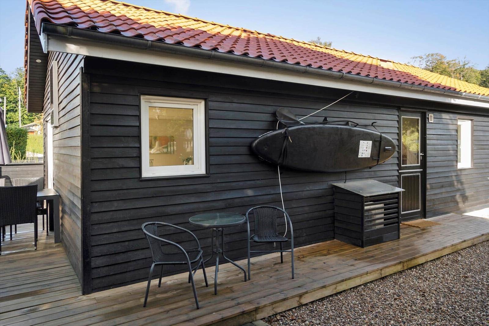 House with wood siding, patio, table, chairs, and kayak mounted on wall.