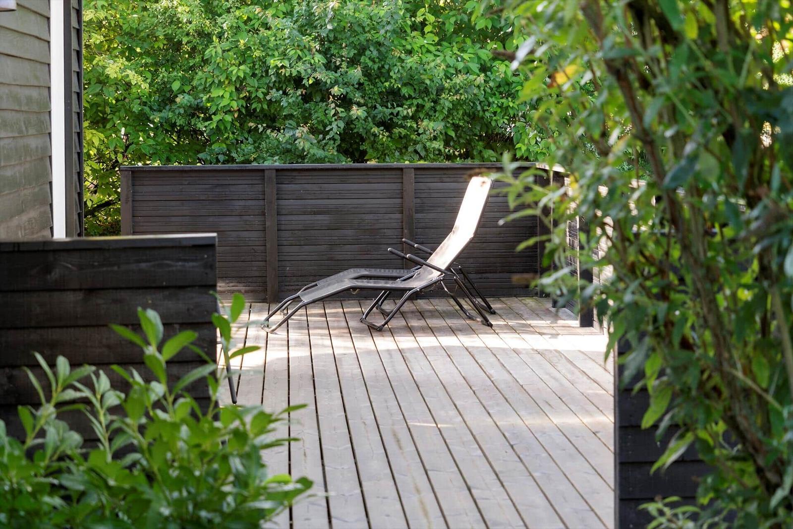 Deck with lounge chairs and green surroundings.