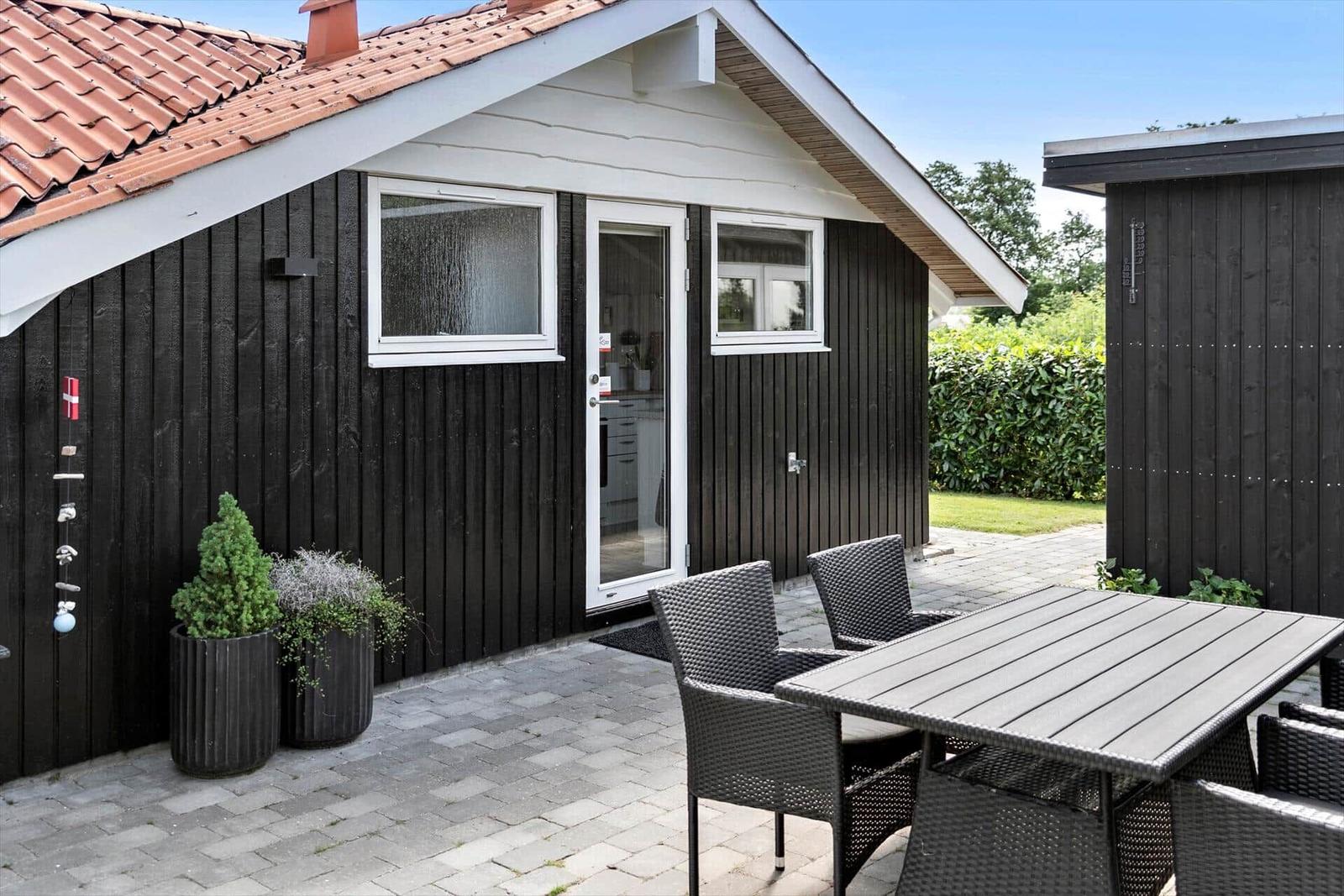 House with terrace, table and chairs, plants and red roof
